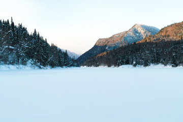 Fototapeta na wymiar Winter landscape with covered river and mountains, Canada