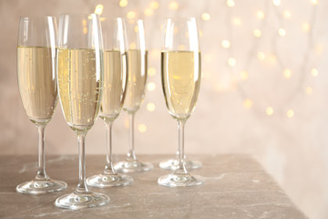 Champagne glasses against blurred lights background, space for text