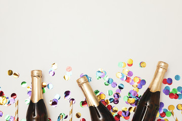 Composition with mini champagne bottles and glitter on white background, copy space