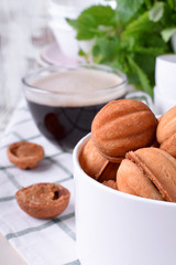 Walnut shaped cookies with condensed milk in a round box and a cup of coffee