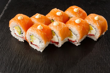 Sushi Rolls with salmon, avocado, flying fish caviar and Cream Cheese inside on black slate isolated. Philadelphia roll sushi with salmon. Sushi menu. Horizontal photo.