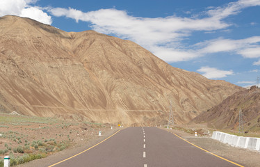 Long straight asphalt road leading to big high mountain