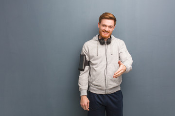 Young fitness redhead man reaching out to greet someone