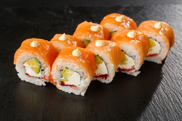 Sushi Rolls with salmon, avocado, flying fish caviar and Cream Cheese inside on black slate isolated. Philadelphia roll sushi with salmon. Sushi menu. Horizontal photo.