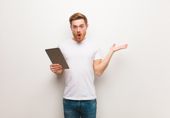 Young redhead man holding something on palm hand. Holding a tablet.