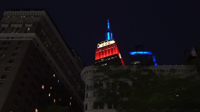 High angle shot of Manhattan rooftops including the colorful illumination of famous skyscrapers and landmark buildings