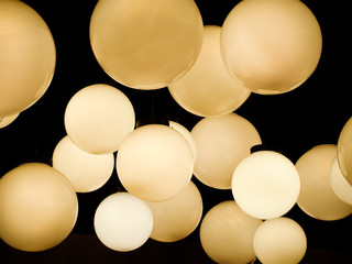Lighting ball hanging from the ceiling on the black background. spheres in warm light. Abstract image.