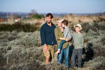Young family with two small children standing outdoors in nature.