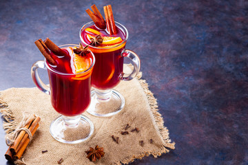 Red mulled wine on burlap. Mulled wine with oranges, cinnamon and cloves on a dark background. Hot...