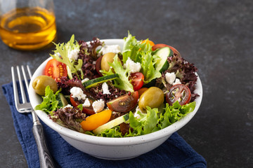 Salad of cucumbers, tomatoes, olives and fresh herbs with olive oil and pepper.
