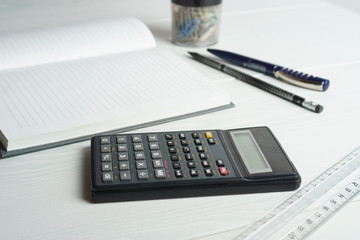 Calculator and notepad on a white table
