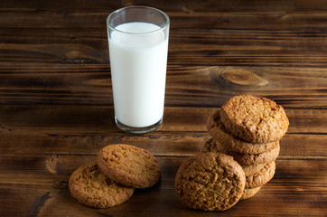 Group of oatmill cookies and milk glass on wooden surface