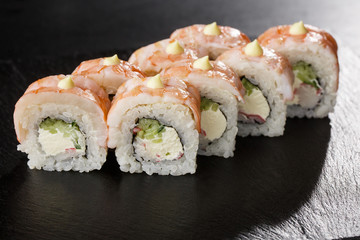 Sushi Rolls with cucumber, shrimp, crab meat and Cream Cheese inside on black slate isolated. Philadelphia roll sushi with shrimp. Sushi menu. Horizontal photo.