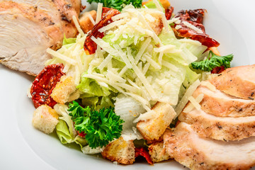 Caesar salad with croutons, quail eggs, cherry tomatoes and grilled chicken on a wooden background