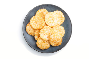Traditional japanese rice chips cookies with honey and soy sauce on a blue ceramic plate isolated on white background. top view.