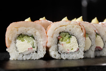 Sushi Rolls with cucumber, shrimp, crab meat and Cream Cheese inside on black slate isolated. Philadelphia roll sushi with shrimp. Sushi menu. Horizontal photo.