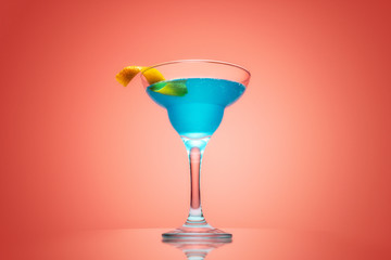 Coctail with blue curacao and decorated with orange peel on red background