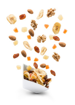 Dried fruits jumping out white bowl on white background