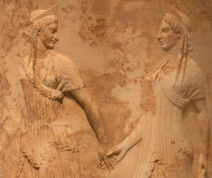 Ancient Greek bas-relief with two female figures (Nymphs or Graces) holding hands and dancing.