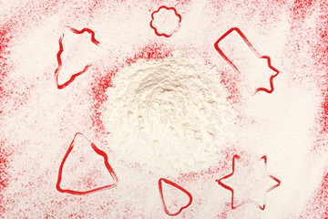 Christmas cookies. Star, tree, bell, heart, flour on a red background. Top view