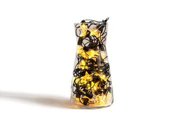 Christmas garland with star shape lamps in a glass transparent vase on white background, holiday festive decor