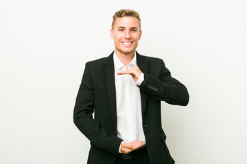 Young caucasian business man holding something with both hands, product presentation.