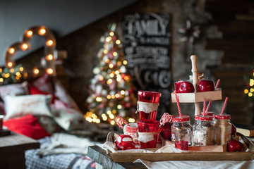 Red Christmas mugs with sweets are on the table on the background of the Christmas tree