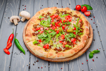 Traditional italian pizza with minced meat on wooden background