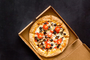 Order pizza to home or office. Italian food in box on black background top view copy space