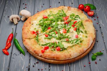 Traditional italian pizza with arugula on wooden background