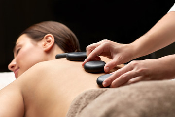wellness, beauty and bodycare concept - close up of woman having hot stone massage at spa