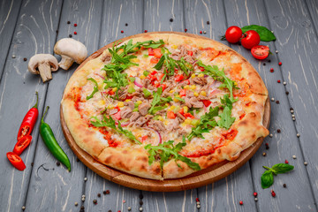 Traditional italian pizza with fish meat on wooden background