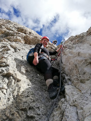 Fototapeta na wymiar attractive blonde female climber on a steep Via Ferrata in the Italian Dolomites