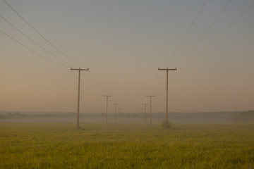 Fototapeta na wymiar Voltage pole with light morning fog
