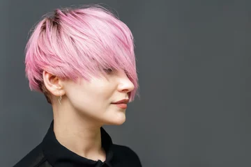 Foto op Canvas Portrait of adult girl with modern short pink hairstyle and closed eyes on the gray background with copy space. © okskukuruza