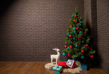 Christmas tree with toys on a background of a brick wall and gifts