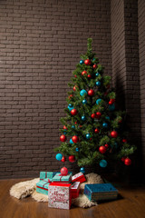 Christmas tree with toys on a background of a brick wall and gifts