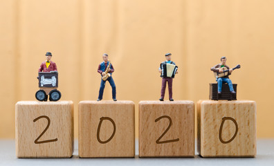 miniature figure music band standing on wooden block with 2020 new year words concepts