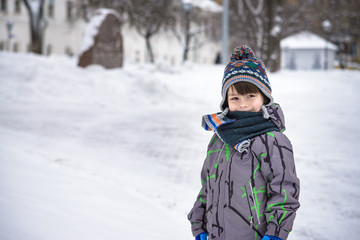 Fototapeta na wymiar Little boy walking in the park. Child going for a walk after school with a school bag in winter. Children activity outdoors in fresh air. Healthy way of life concept