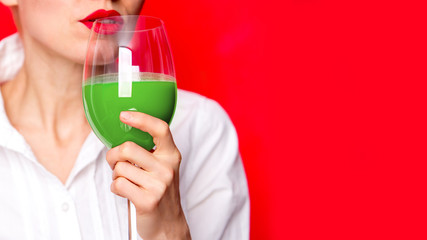 Girl hold green celery juice in glass over red background
