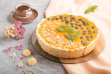 Traditional american sweet pumpkin pie decorated with mint, sesame and pumpkin seeds on a gray concrete background. side view, close up.