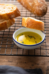 Freshly baked white bread with olive oil and herbs on wooden background.