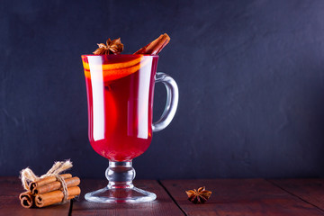 Mulled wine with cinnamon sticks on dark background. Christmas mulled wine with orange, star anise...