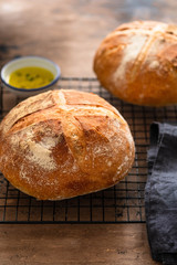 Freshly baked traditional bread and olive oil on wooden table.