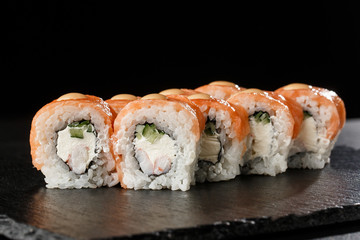 Sushi Rolls with cucumber, shrimp, salmon and Cream Cheese inside on black slate isolated. Philadelphia roll sushi with shrimp. Sushi menu. Horizontal photo.