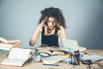 girl hand in hair with books on desk