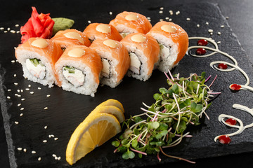 Sushi Rolls with cucumber, shrimp, salmon and Cream Cheese inside on black slate isolated. Philadelphia roll sushi with shrimp. Sushi menu. Horizontal photo.