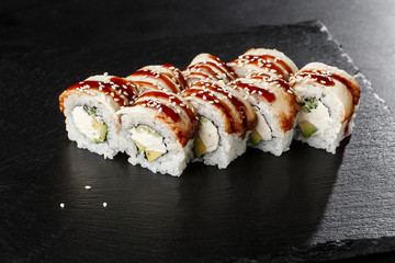 Sushi Rolls with cucumber, avocado, eel and Cream Cheese inside on black slate isolated. Philadelphia unagi roll sushi with shrimp. Sushi menu. Horizontal photo.