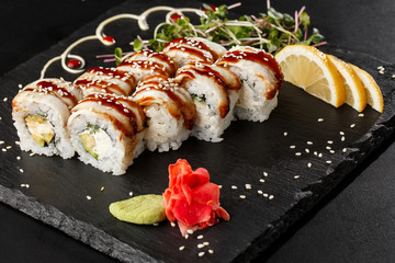 Sushi Rolls with cucumber, avocado, eel and Cream Cheese inside on black slate isolated. Philadelphia unagi roll sushi with shrimp. Sushi menu. Horizontal photo.