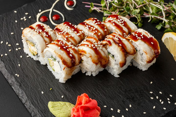 Sushi Rolls with cucumber, avocado, eel and Cream Cheese inside on black slate isolated. Philadelphia unagi roll sushi with shrimp. Sushi menu. Horizontal photo.
